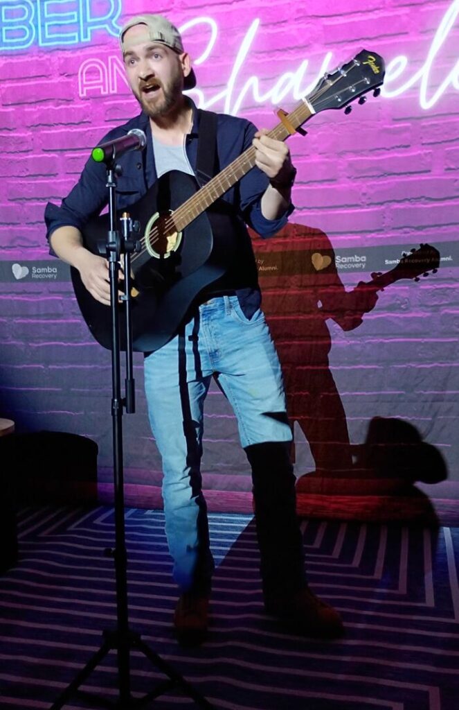 Sam Daniel playing guitar and singing at the Samba Recovery Savannah alumni event